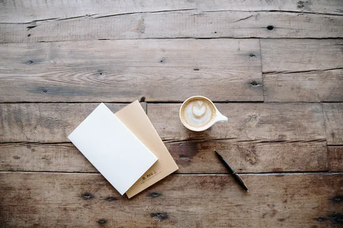 An open notebook and pen beside a coffee cup